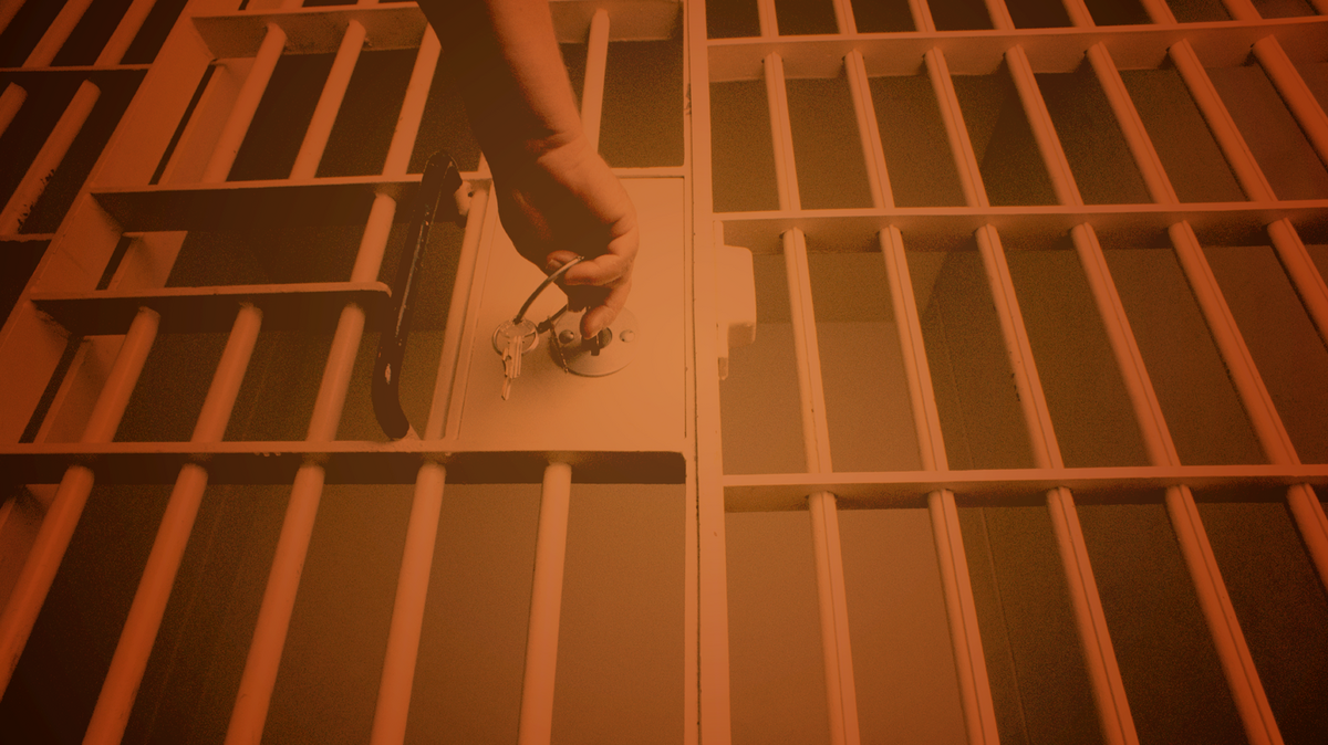 Bars from a jail cell frame a door being locked.